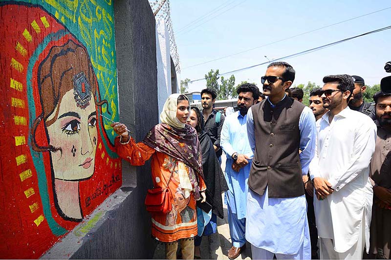 Students painter briefs Assistant commissioner Rao Hashim about his painting during the Wall Chalking Competition in front of Khyber Teaching Hospital organized by District Youth Affairs in collaboration with District Administration