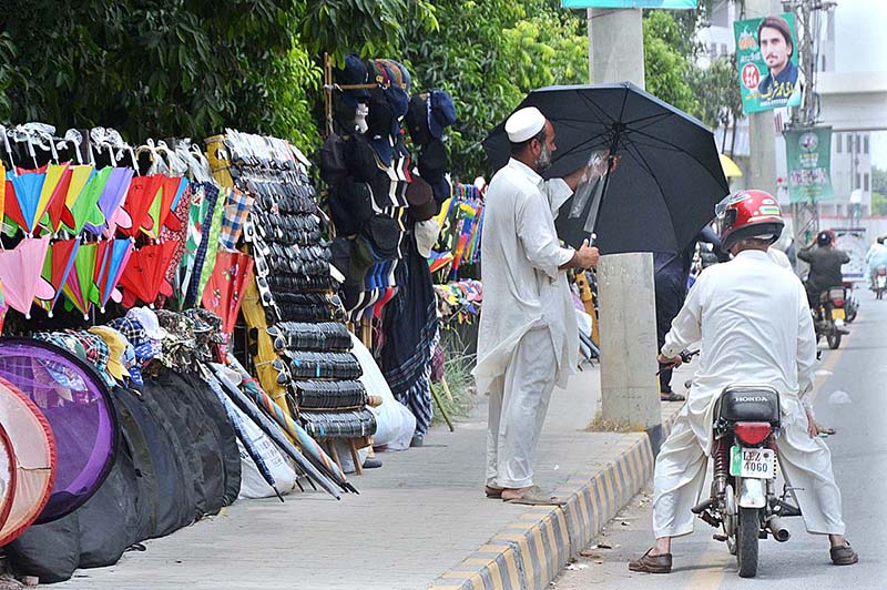 A vendor displaying and selling umbrellas during hot weather in the city