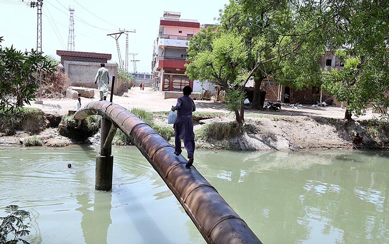 A youngster crossing the canal through water supply pipeline at Mirpurkhas Road