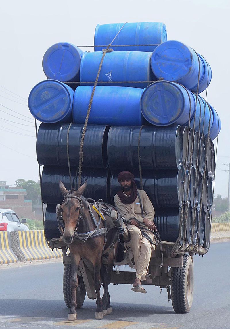A donkey cart holder loaded with empty drums going towards his destination