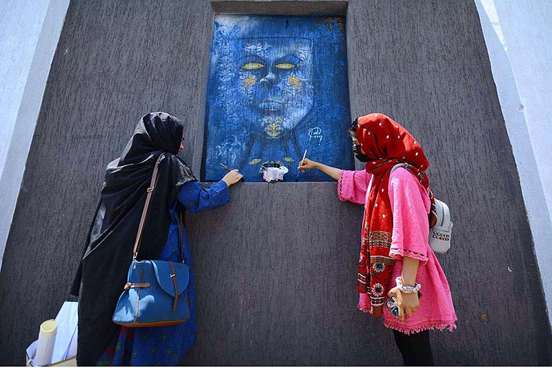 Students painter briefs Assistant commissioner Rao Hashim about his painting during the Wall Chalking Competition in front of Khyber Teaching Hospital organized by District Youth Affairs in collaboration with District Administration