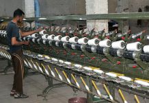 A factory worker making thread reels on the machine