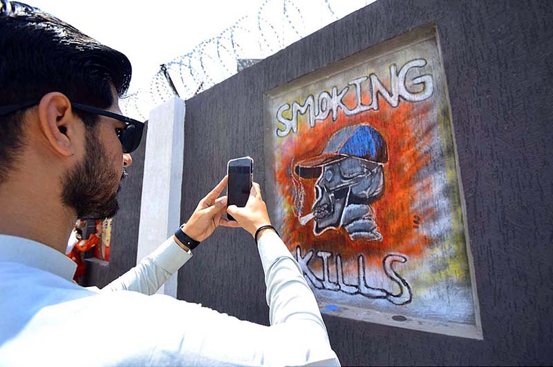 Students painter briefs Assistant commissioner Rao Hashim about his painting during the Wall Chalking Competition in front of Khyber Teaching Hospital organized by District Youth Affairs in collaboration with District Administration