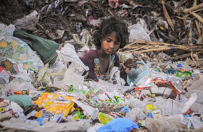 Gypsy girl searching valuables from the heap of garbage