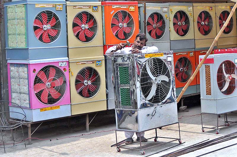 A worker busy in preparing a room cooler at his workplace as demand increases in the summer season