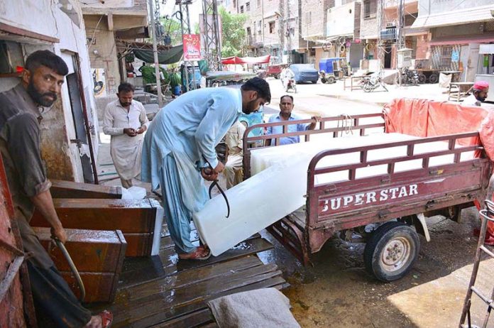 Labourer busy in loading ice-block on the Tri-cycle rickshaw outside ice factory