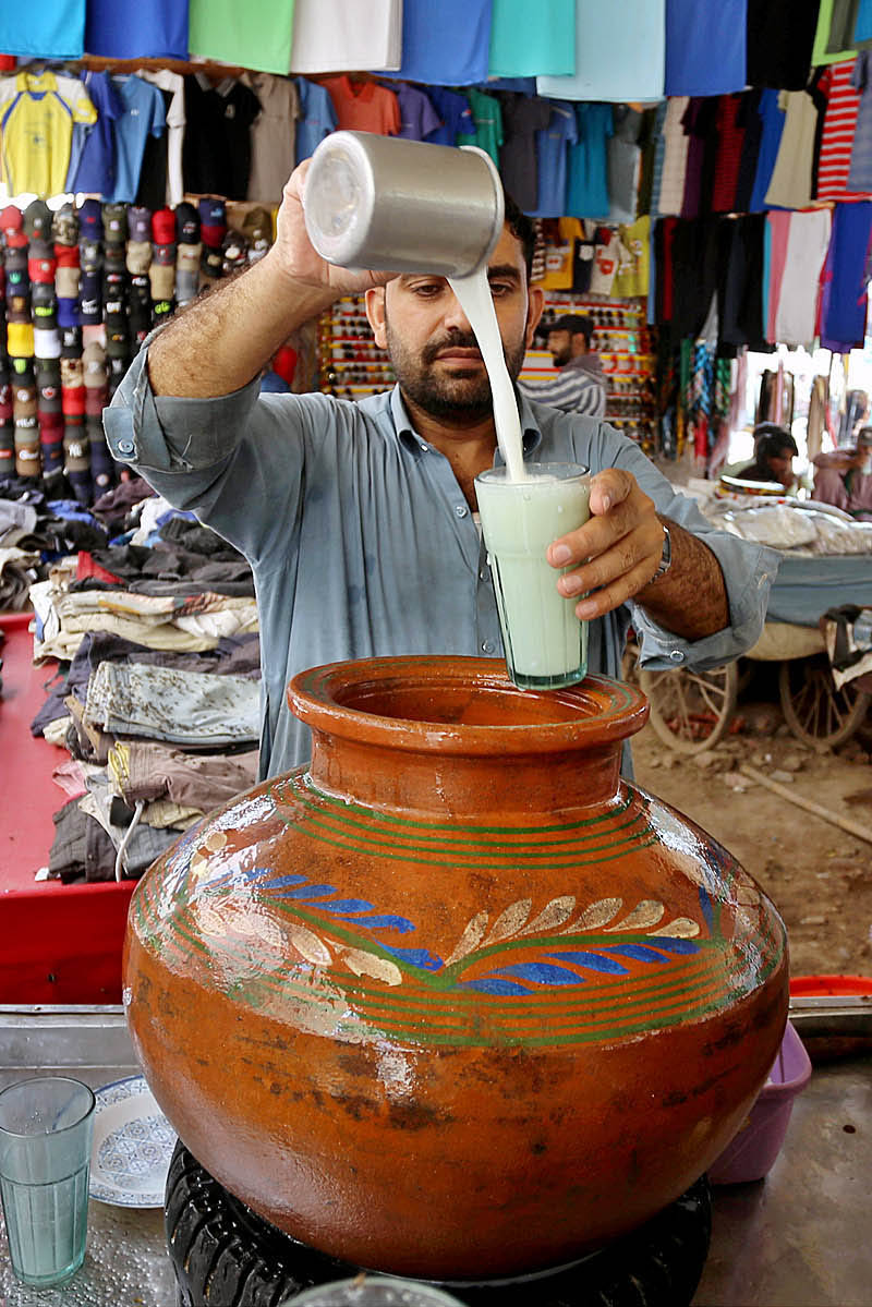 A roadside vendor making traditional drink buttermilk (Lassi) to attract the customer at under the flyover Makkis road
