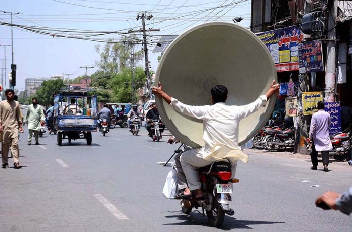 A person holding a dish antenna while sitting on the rear seat of motorcycle