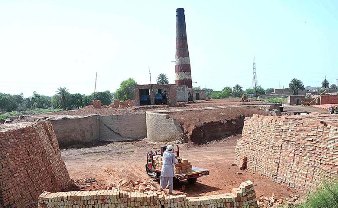 Labourer busy in loading bricks on a tricycle loader to deliver to the customer at local bricks kiln