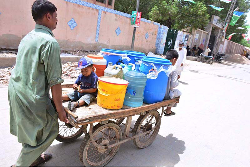 A person pushing hand cart loaded with water canes after filling clean water from filter at Latifabad