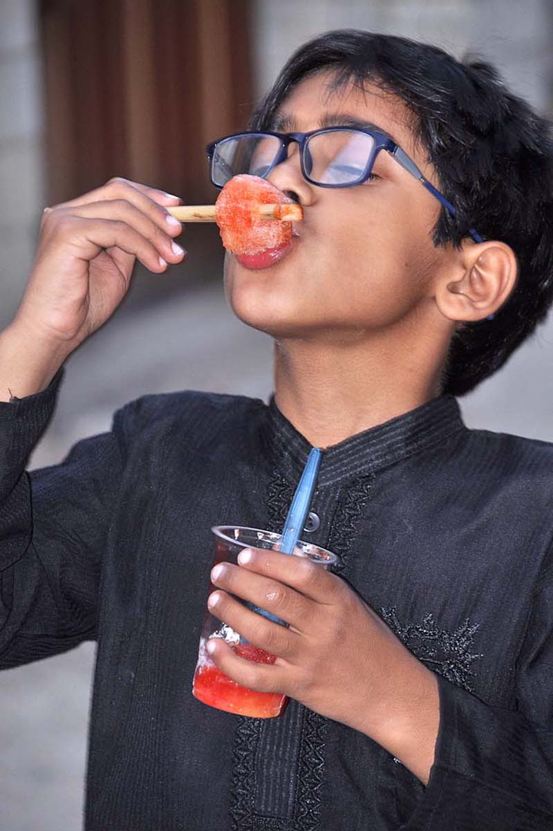 A boy is eating ice gola from a street vendor at Tewana Park