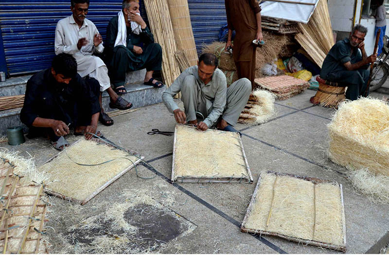 Workers busy in refilling husk in frames of air coolers at his workplace to keep air cool where the temperature is high and humidity is low in summer season