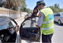 Traffic police removing black sheets from vehicle windows during crackdown against black glasses and Applied for vehicles at Charsadda road