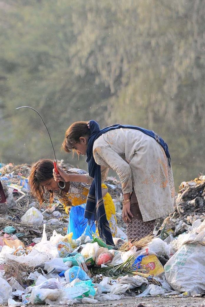 Gypsy girls searching for valuables from the heap of garbage