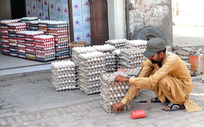 A shopkeeper busy in binding the crates of eggs to deliver in the market at his shop