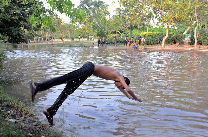 Youngsters jump into the canal for bathing to get some relief from hot weather in the city