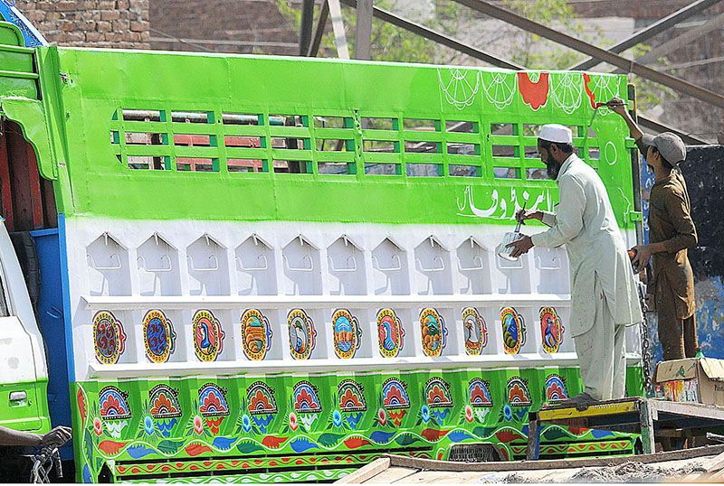 Painters are busy in truck art at the body of a mini truck at his workplace