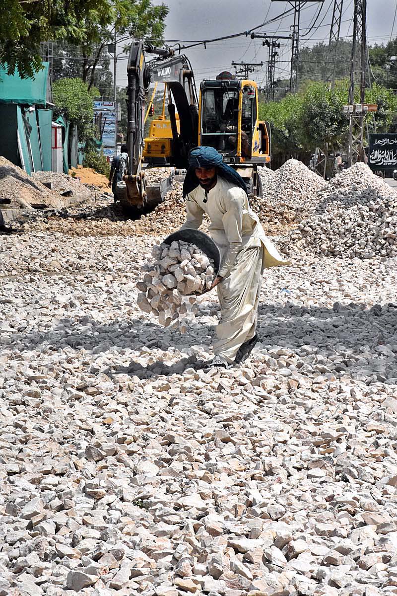 A labourer busy in construction work of Sachal Colony Road during development work in the City