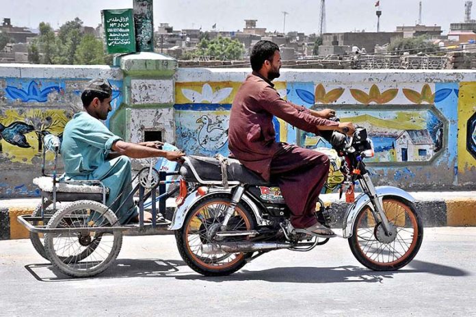 A disable person on his wheelchair holding a motorcycle while travelling on road