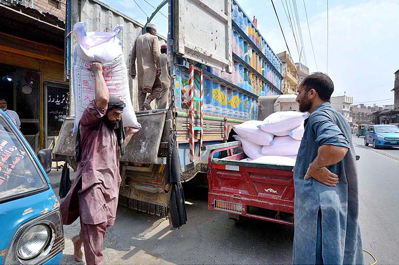 Labourer busy in loading flour sacks from truck to delivery tri-wheeler at Rampura Gate on International Labour Day