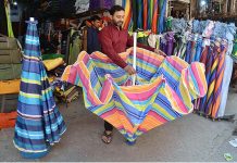 A vendor is displaying colorful umbrellas to attract customers at Landa Bazaar