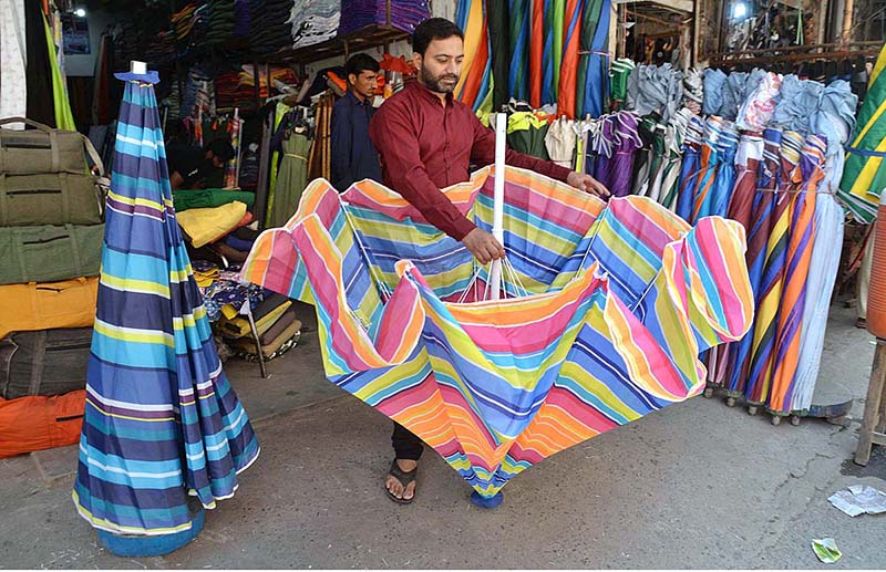 A vendor is displaying colorful umbrellas to attract customers at Landa Bazaar