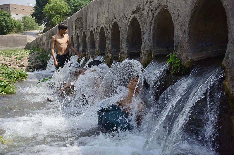 Youngsters enjoying a bath in a stream to get relief from hot weather at Inqilab Road