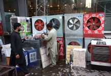 A worker is preparing room coolers at his workplace due to its increasing demand during summer season