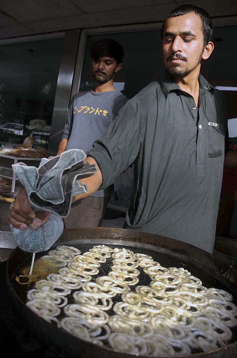 A vendor busy in preparing traditional food item (jalebi) to attract the customers at Gawal Mandi Bazaar