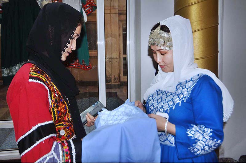 A visitor taking interest in a traditional Hazaragi costume displayed at a handicraft stall during the Hazara Culture Day at PNCA