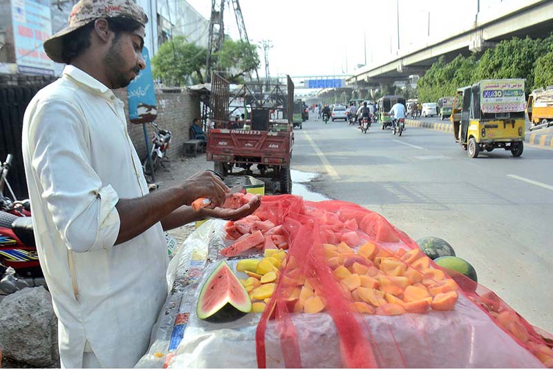 A roadside vendor cutting and displaying watermelon to attract the customer at his setup