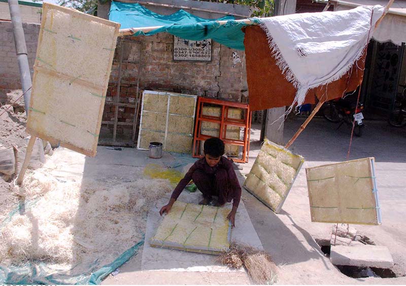 A youngster making windows of air coolers to earn bread for his family at roadside