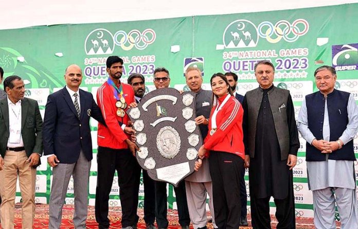 President Dr. Arif Alvi giving the winner's trophy to the Pakistan Army team, at the closing ceremony of the 34th National Games