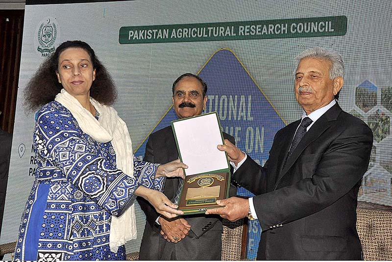 Federal Minister for Education and Professional Training Rana Tanveer Hussain giving a shield to a female participant at 3-day seminar on "National Dialogue on Agricultural Research" at PARC