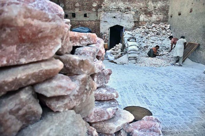 Labourer crushing Pink rock salt and fill it in the bags to transport in the market at Provincial Capital City