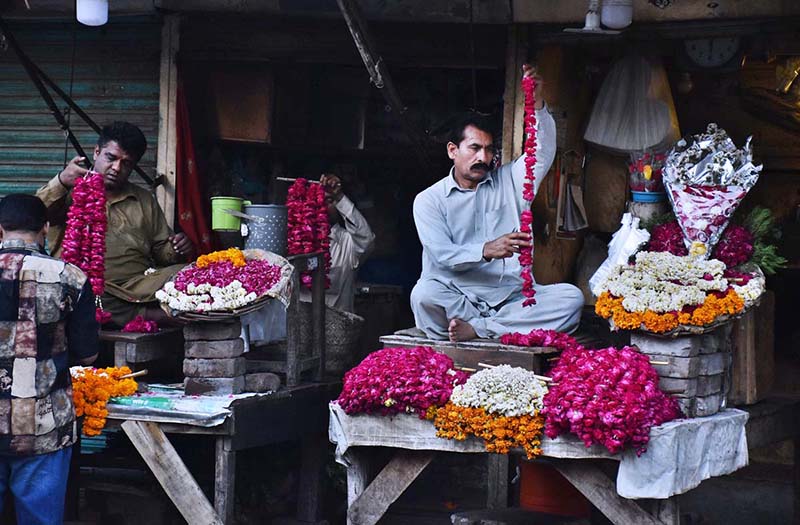 A shopkeeper is busy in making flower garlands to attract the customer at Lohari Chowk