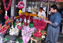 A shopkeeper is displaying flower garlands to attract the customer at Lohari Chowk