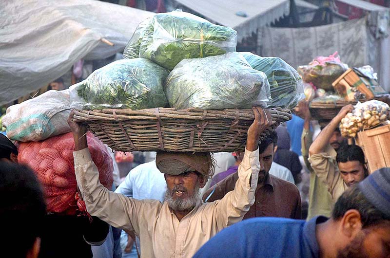Labourers carrying basket of vegetables on his head to earn livelihood at Vegetable Market in the city