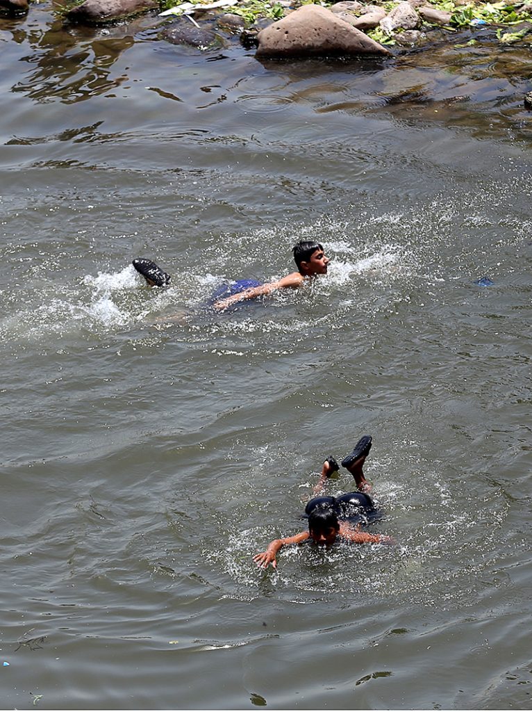 Youngsters swimming in a pond of water to keep themselves cool during a hot weather near Rawal Dam