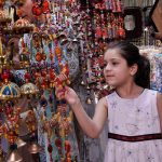 Young girl showing keen interest in traditional stuff on stall during Saqafati Mela promoting Pakistani culture providing entertainment to public at Lok Virsa
