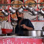A vendor making tea for costumers at his workplace in the Federal Capital