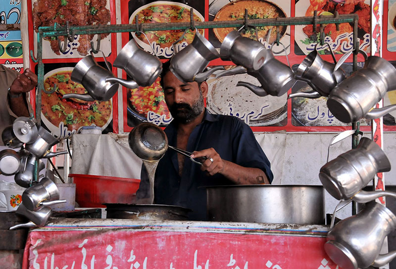 A vendor making tea for costumers at his workplace in the Federal Capital