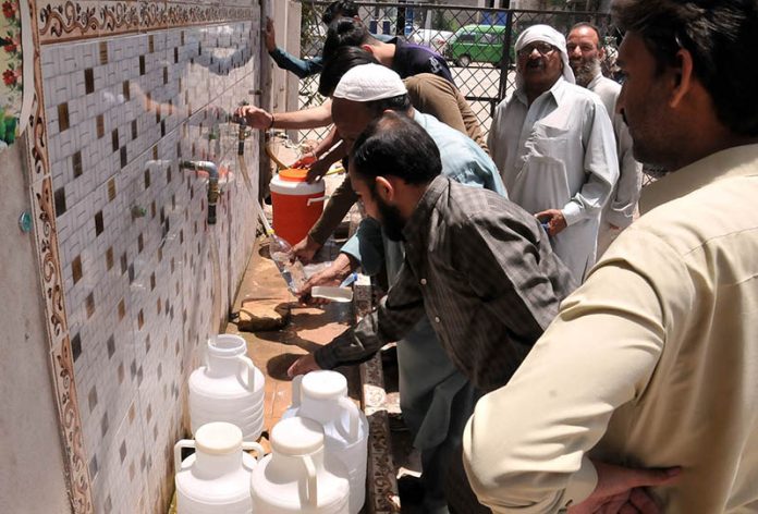 People filling drinking water from filtration plant at Ghori town during hot day in the Federal Capital