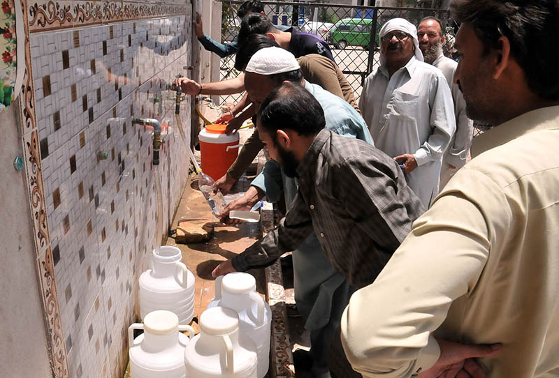 People filling drinking water from filtration plant at Ghori town during hot day in the Federal Capital