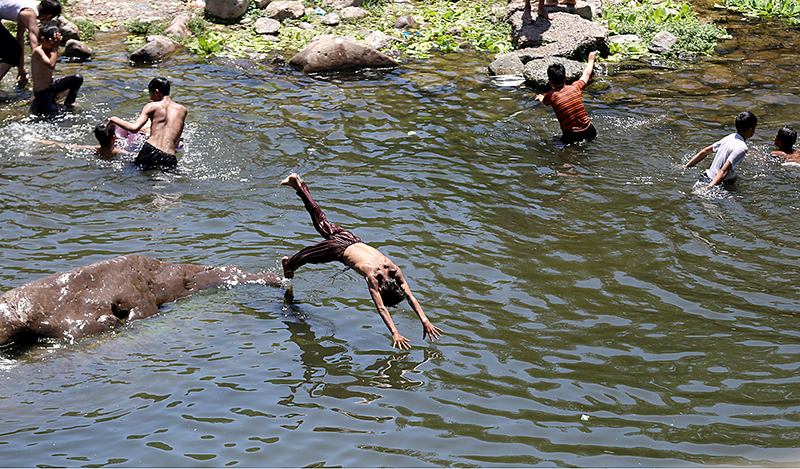 Youngsters swimming in a pond of water to keep themselves cool during a hot weather near Rawal Dam
