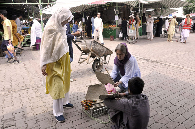 Women busy in purchasing handmade fan at H-9 weekly bazar during hot weather in the Federal Capital.