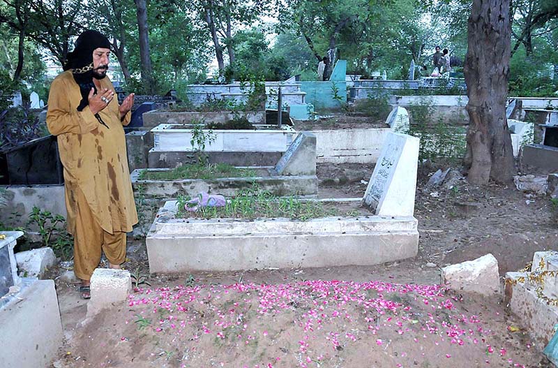 People reciting Holy Quran and offering fateha on the graves of their family members in graveyard on the occasion of Eid ul Azha