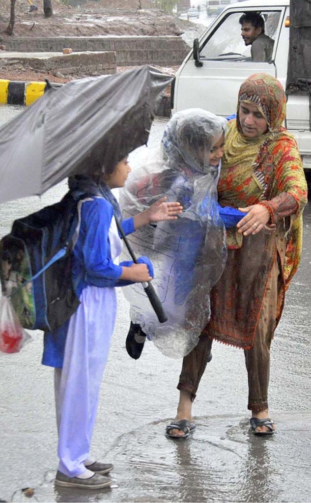 A woman carrying her daughter faces a challenging task of crossing stagnant water amidst heavy rainfall at IJP road