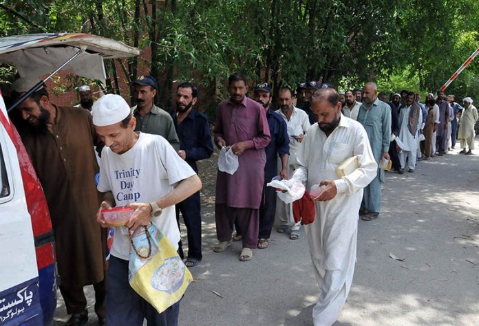 A volunteer distributing free food among deserving people at Mauve Area G-7