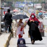 A girl on the way under cover of an umbrella to protect herself from direct sunlight during a hot weather at Ghouri Town